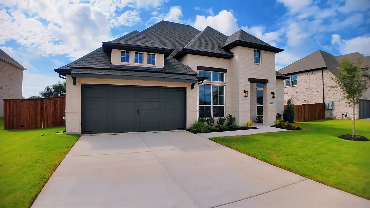 Front exterior of a light brick home with dark garage door and large front windows