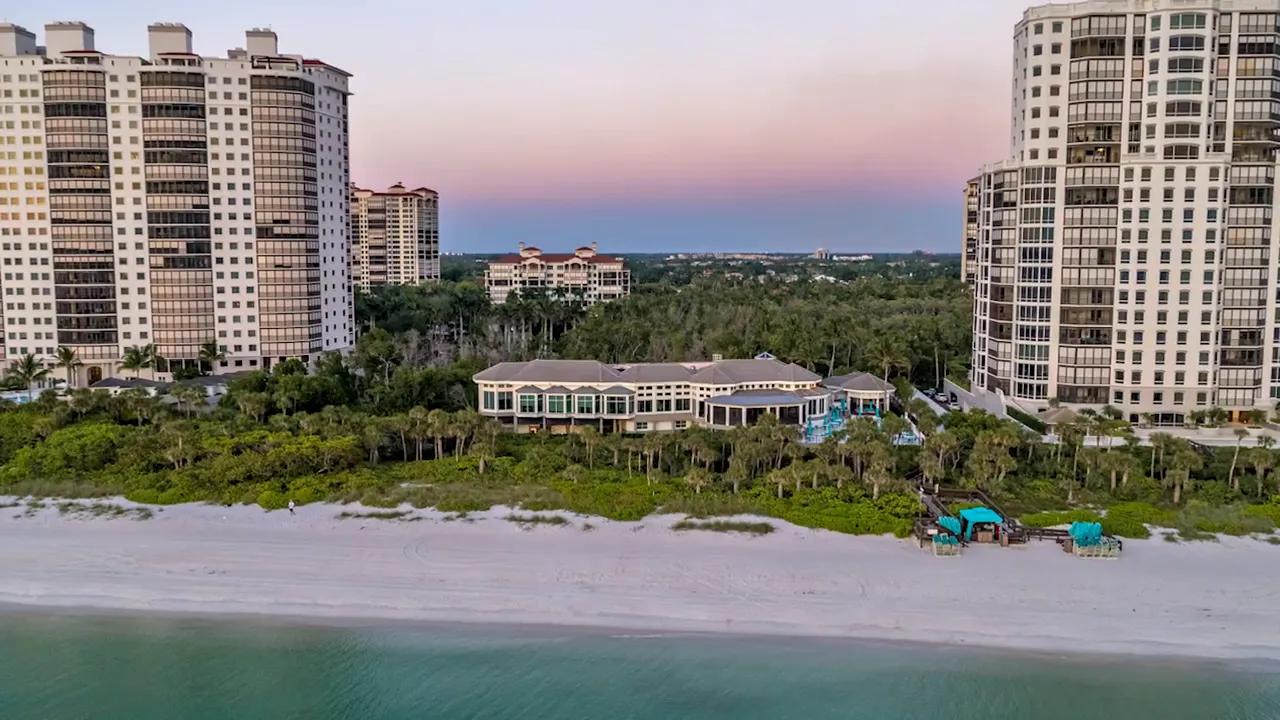 Aerial view of a Naples beachfront high-rise community overlooking sand, ocean water, and resort-style amenities