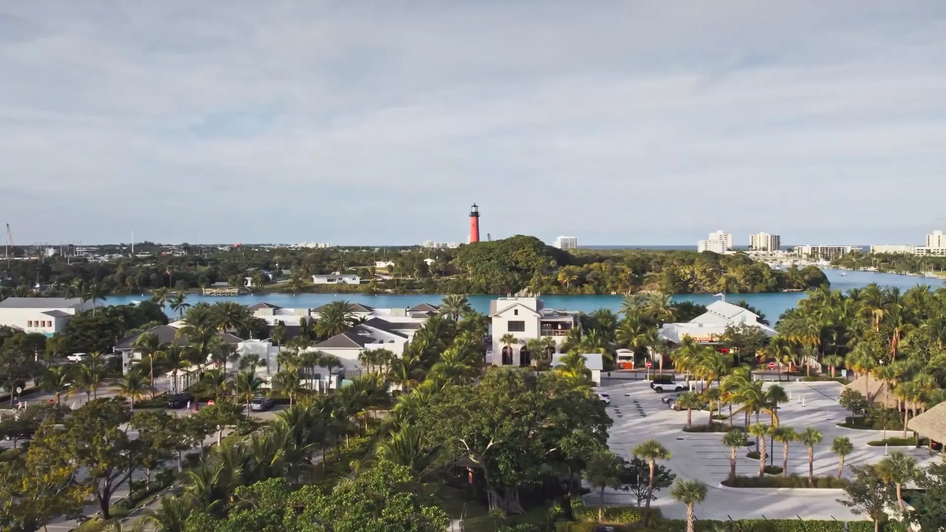 high-quality aerial view of waterfront homes, inlet and a prominent red lighthouse near Tequesta