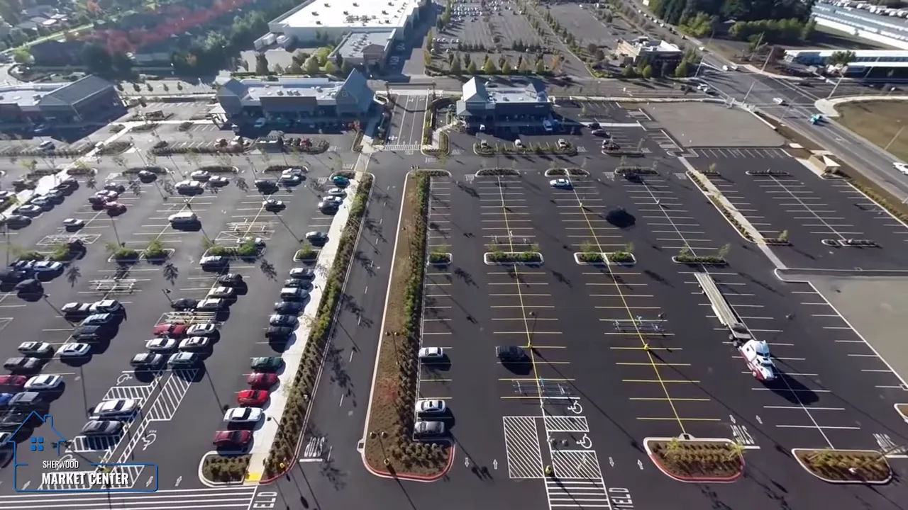 Aerial view of large shopping center parking lots and retail buildings