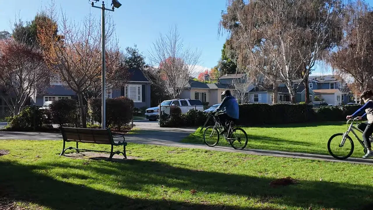 Cyclists riding on a sunny South Bay neighborhood path with houses and hedges