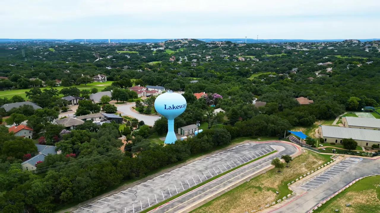 Aerial photo of Lakeway water tower and surrounding homes with rolling, tree-covered hills