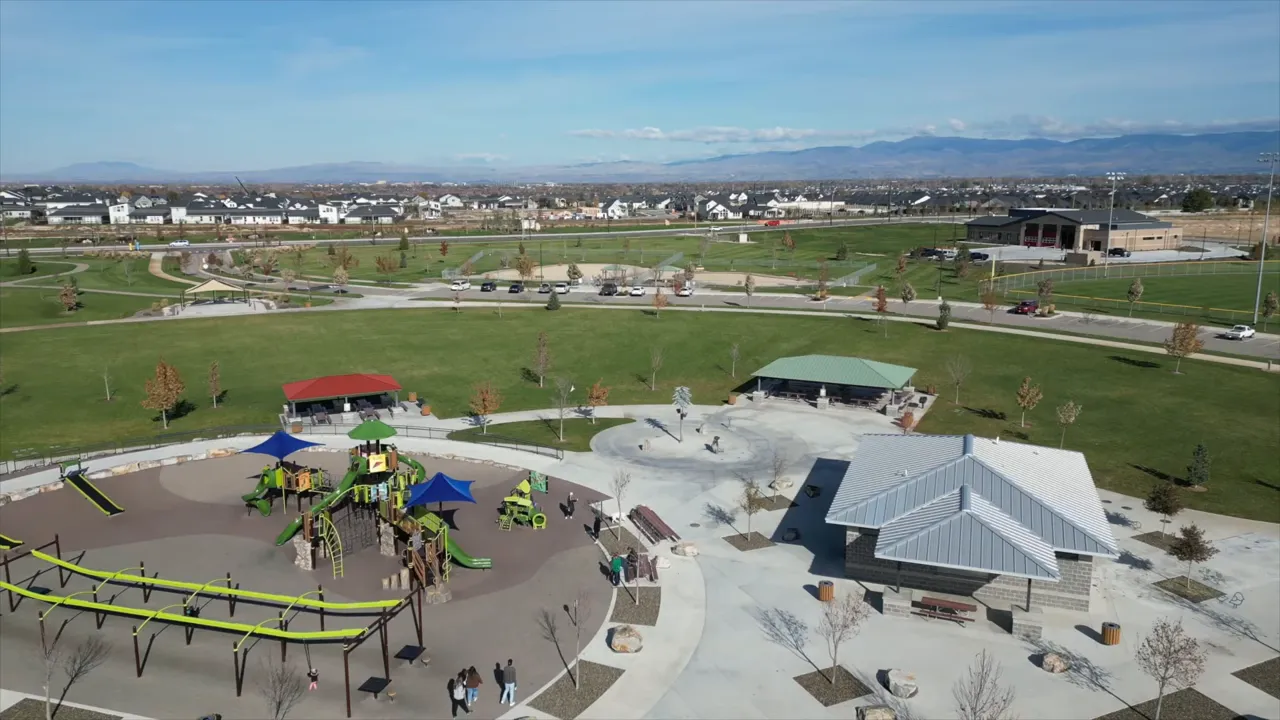 Aerial view of large park with splash pad playground shelters and surrounding paths