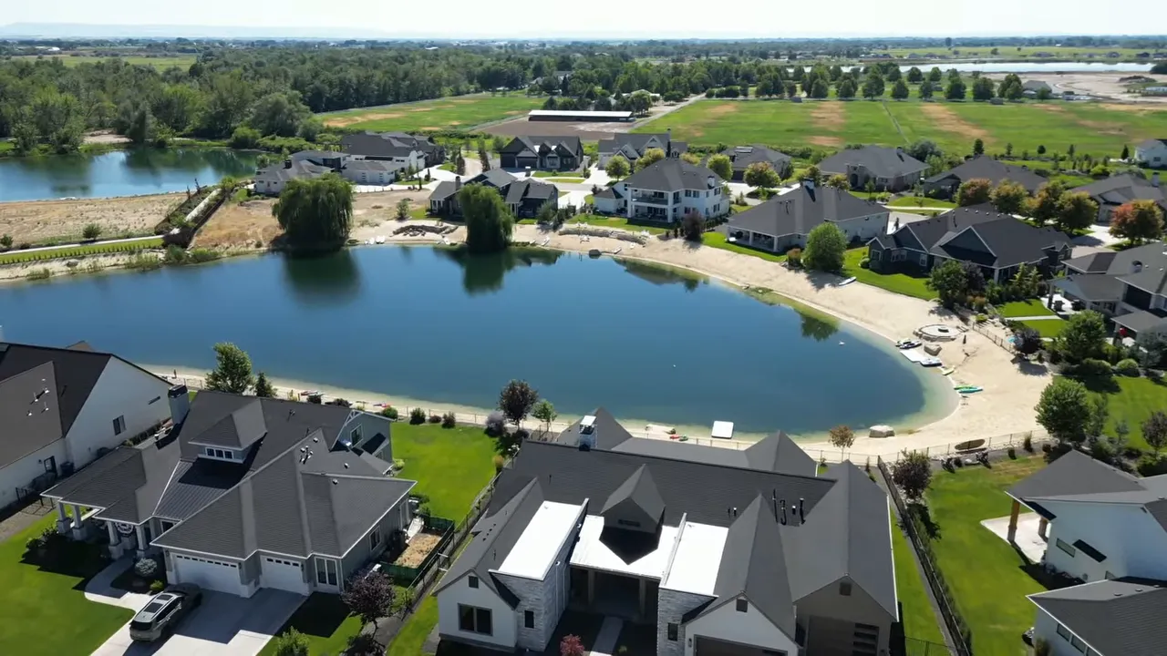 Neighborhood homes surrounding a blue lake with sandy beach and water access