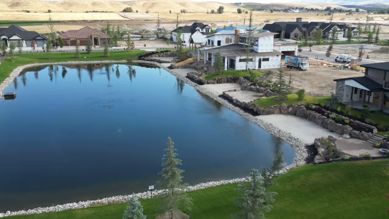 Large community lake with sandy shoreline and luxury homes under construction nearby