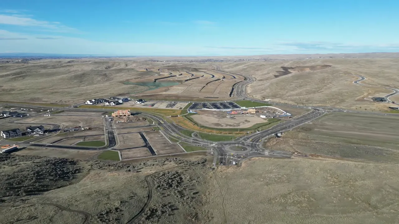 Wide aerial view of foothills development with roads buildings and surrounding hills