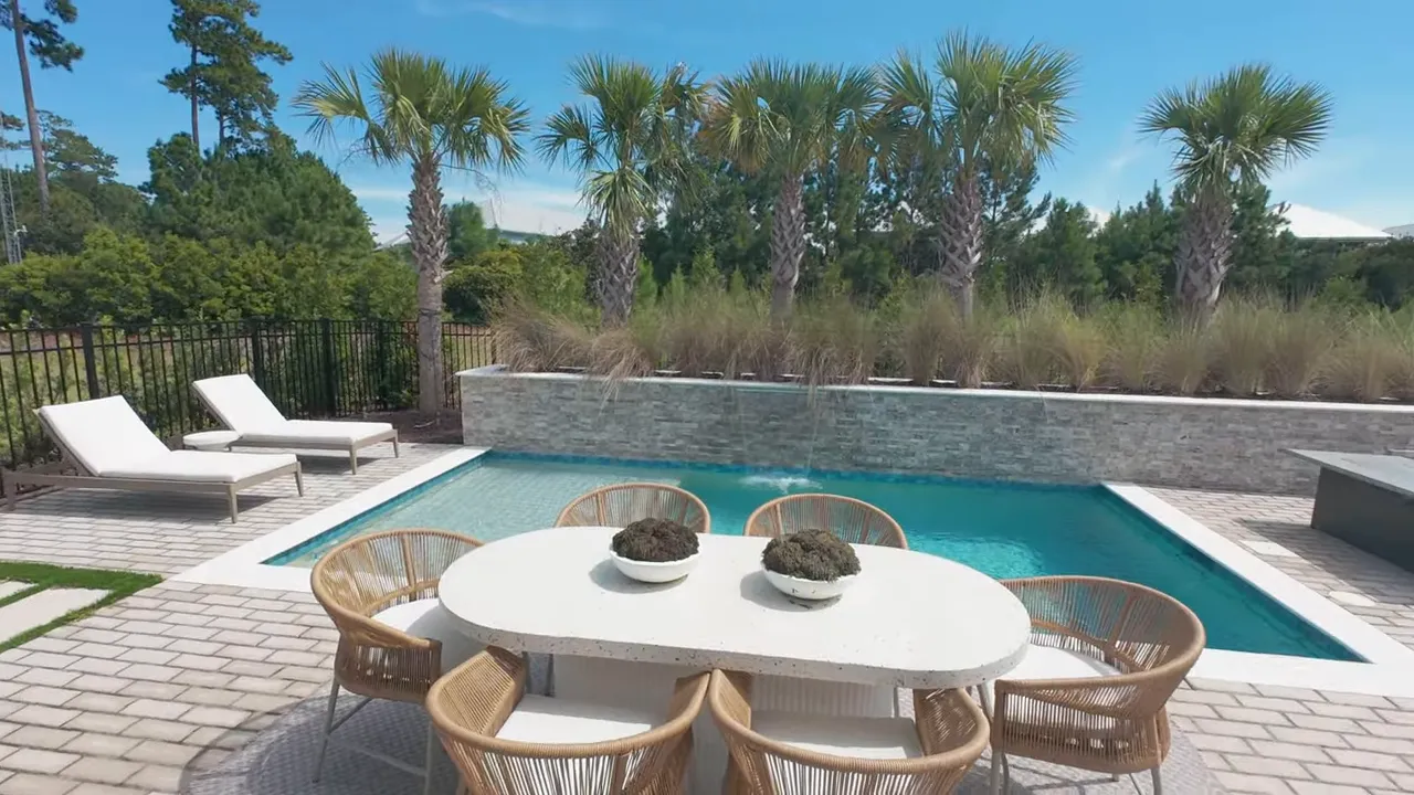 Small rectangular pool surrounded by lounge chairs and paved patio