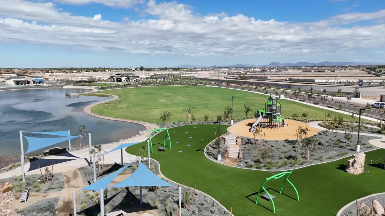 Aerial view of a lakeside park with green lawns playground equipment and neighborhood homes