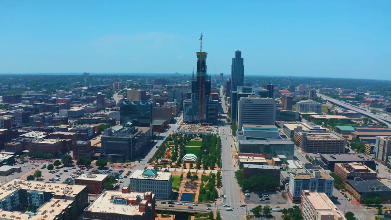 Wide aerial view of Downtown Omaha showing the 44-story tower under construction with park space in the foreground