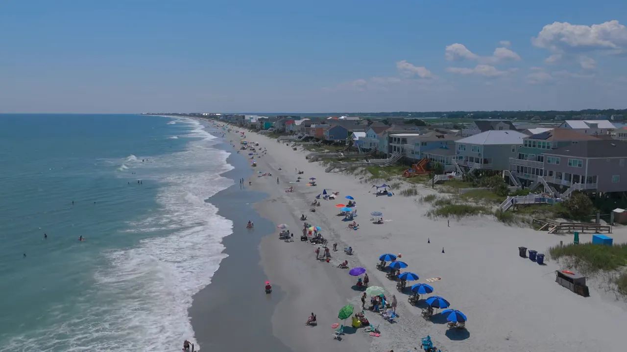 Aerial view of a busy beach with umbrellas and ocean waves