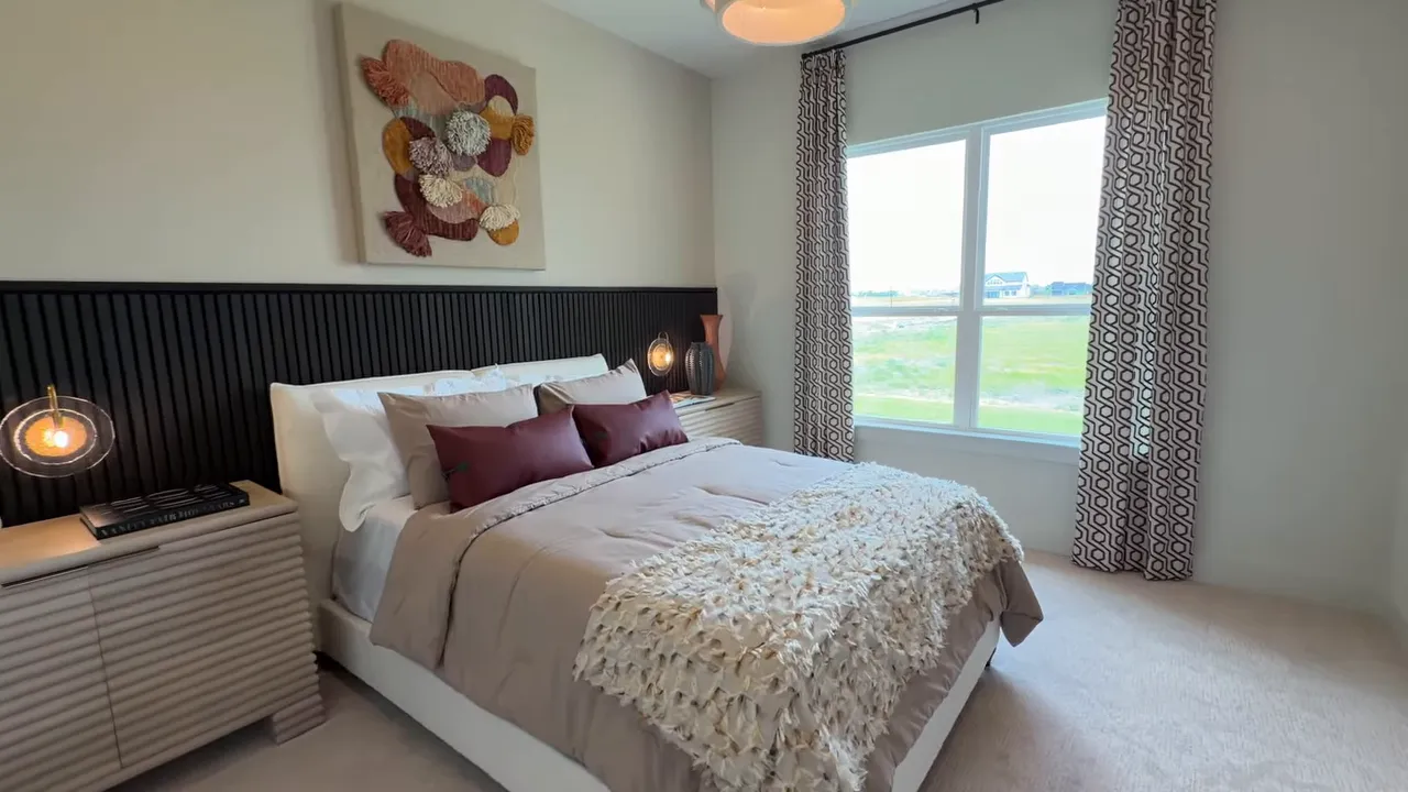 Secondary bedroom with bed, decorative headboard, and large windows in the Lancaster one-story home model in McLendon-Chisholm TX