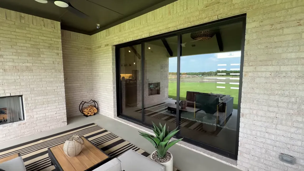 Covered patio entertaining area with sliding glass doors and outdoor seating overlooking the backyard