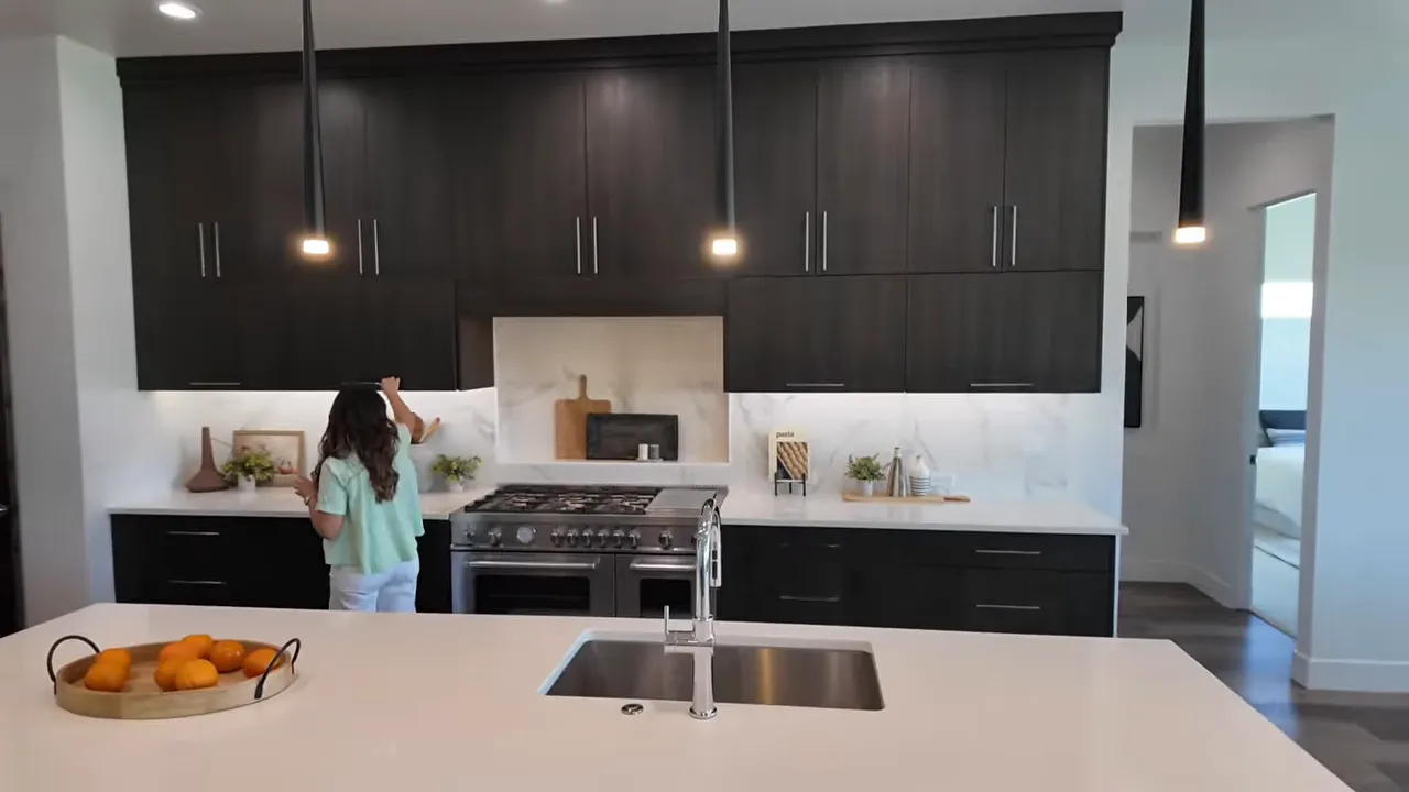 Kitchen with dark custom cabinets large range white countertops and island sink