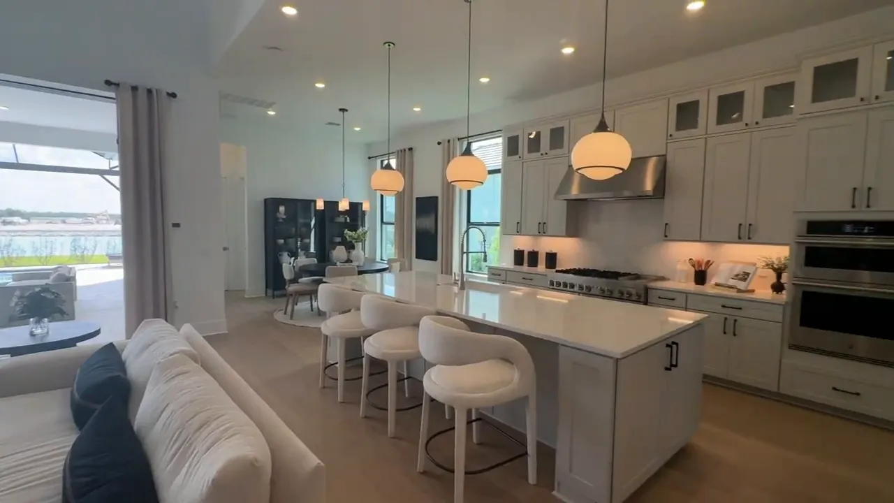 Large white kitchen with island bar stools high ceiling and pendant lights