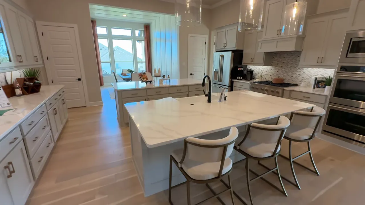 Spacious Catalina kitchen with large marble island, three bar stools, pendant lights and open sightline to the dining area.