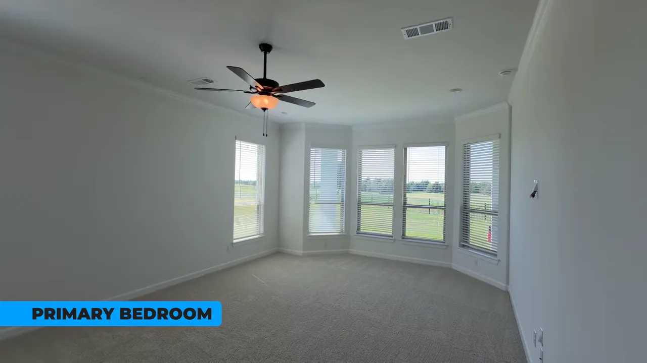 Primary bedroom interior with ceiling fan and wide windows overlooking the green space at Heath Golf & Yacht Club