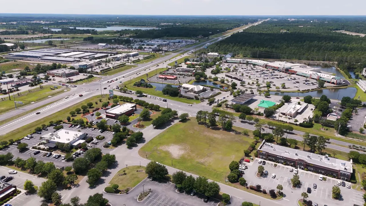 Aerial view of commercial shopping area and parking lots near major road