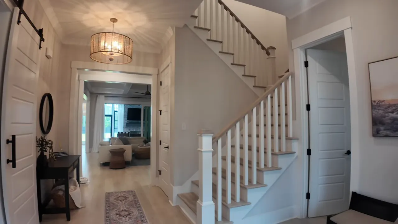 Bright foyer with staircase, hallway, and barn door opening near the front entry
