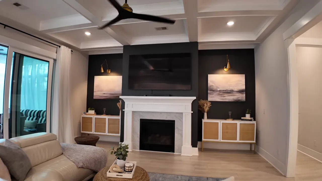 Living room with coffered ceiling, fireplace, wall mounted television, and built in cabinets