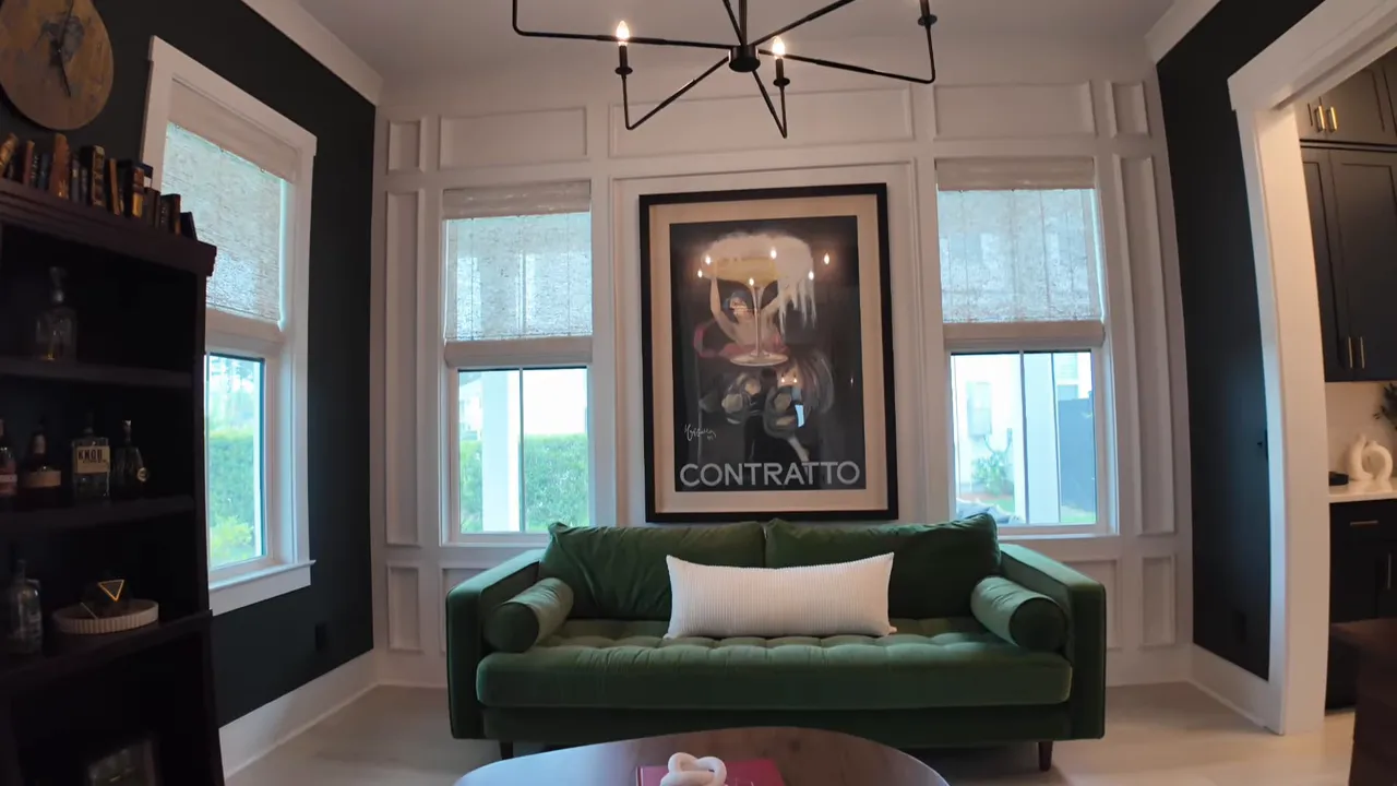 Dark accent flex room with green sofa, framed wall art, chandelier, and multiple windows