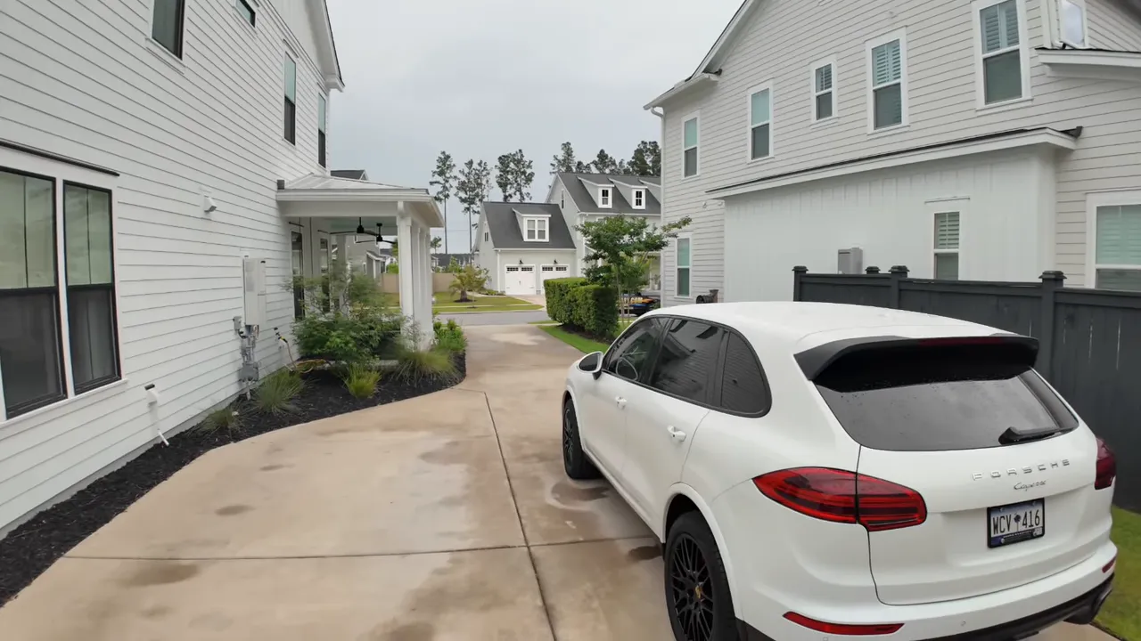 Long driveway beside the house leading to detached garage and parked white suv