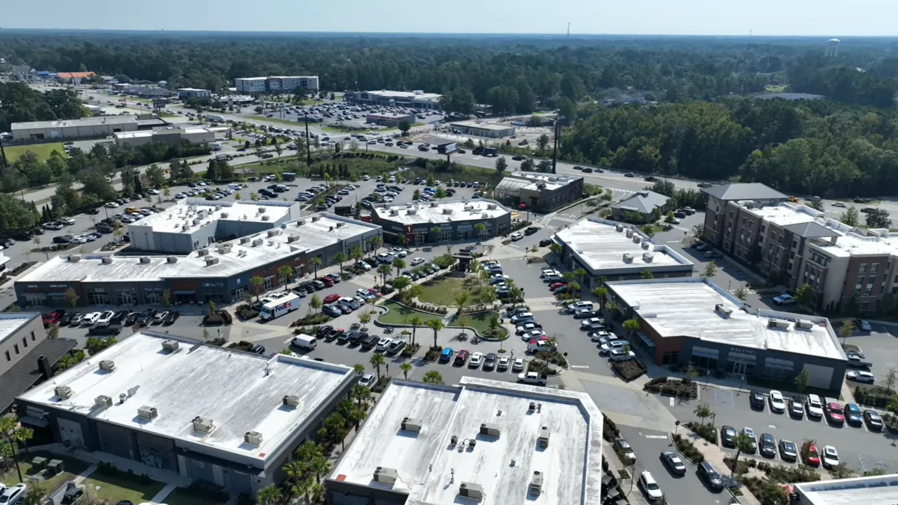 Aerial view of shopping and mixed use area with roads parking and buildings
