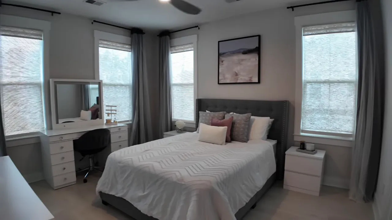 Upstairs bedroom with bed, desk vanity, and windows on two walls