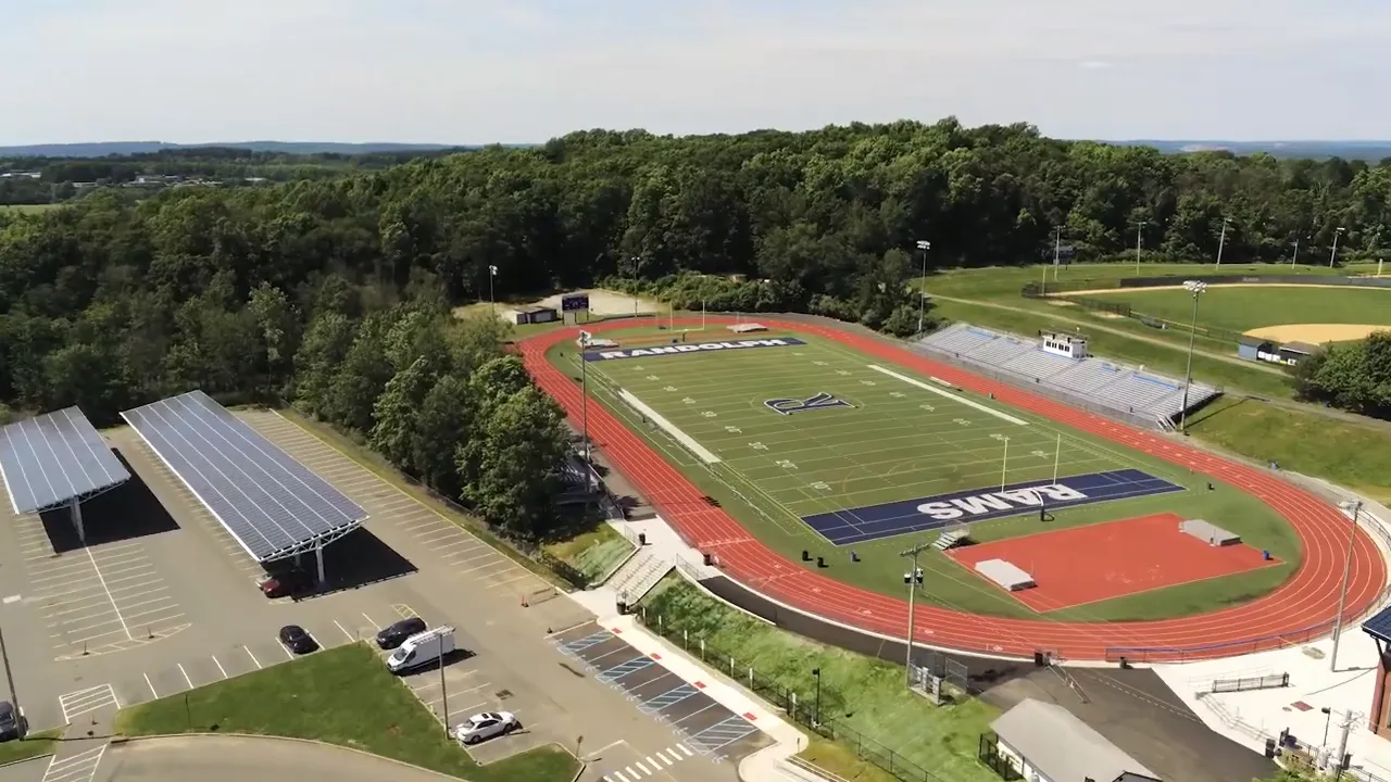 Aerial view of school campus with track football field parking and adjacent athletic fields