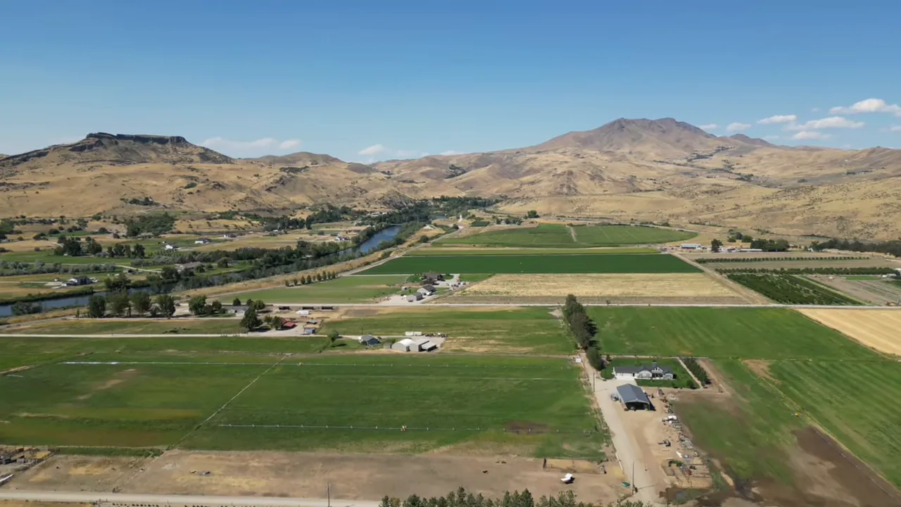 Aerial view of Emmett-area farmland, river and surrounding foothills under a blue sky