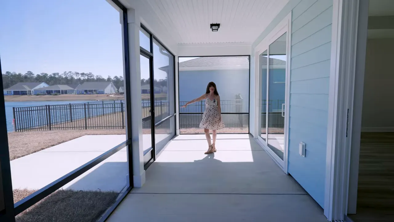 Wide view of screened porch showing covered patio flooring and backyard water view