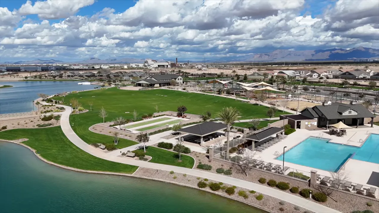 Aerial view of a lakeside community park with green fields and swimming pool