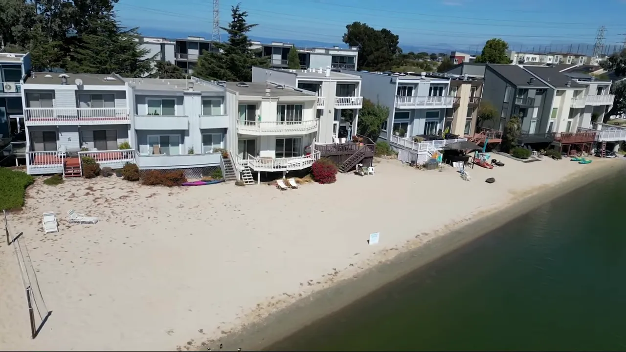 Sandy lagoon shoreline with beachfront homes and calm water in San Mateo
