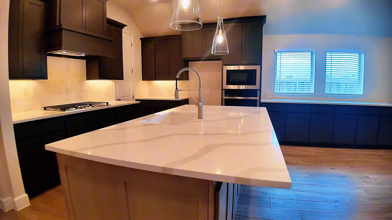 Large kitchen island with veined countertop two tone cabinets and pendant lighting