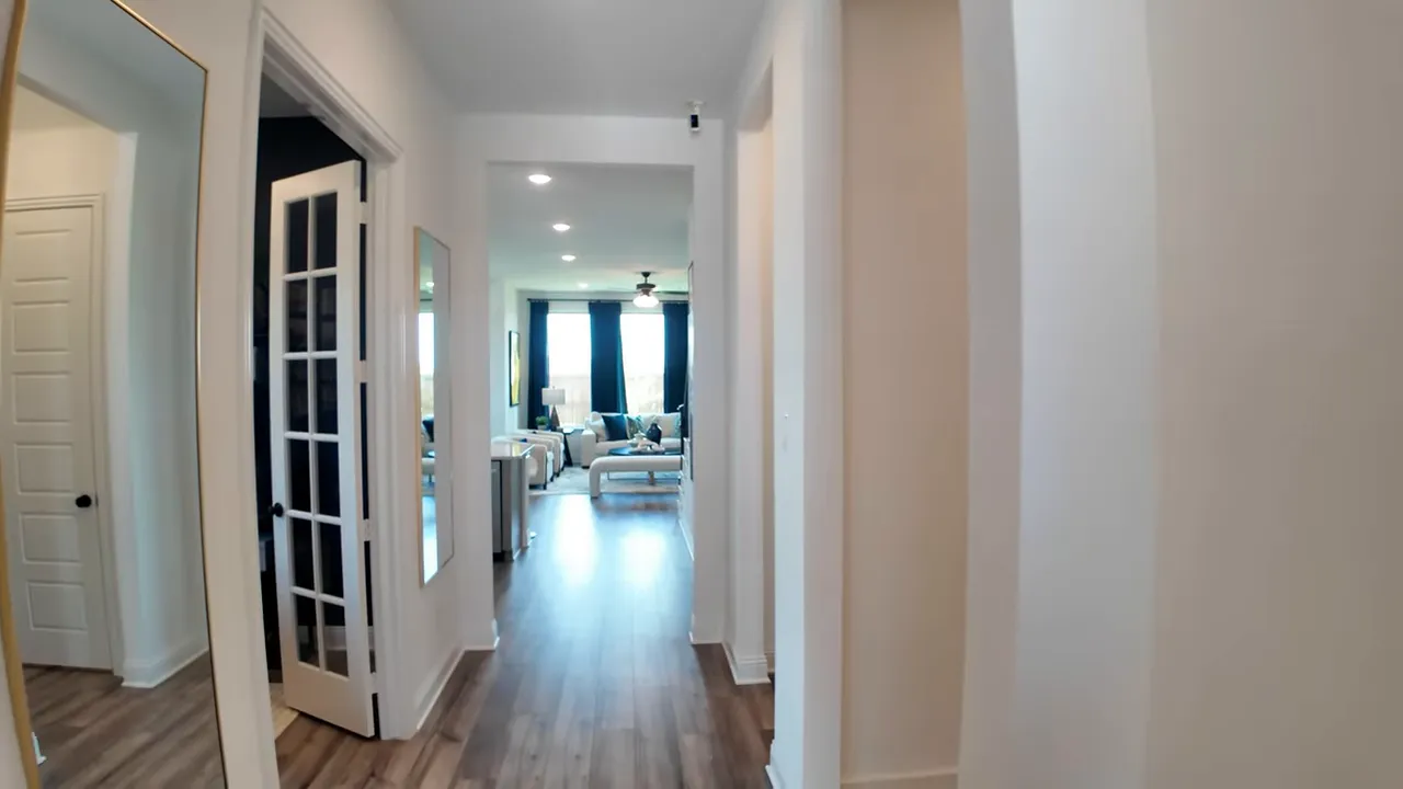 long entry hallway with wood look floors glass office doors and living room visible in distance