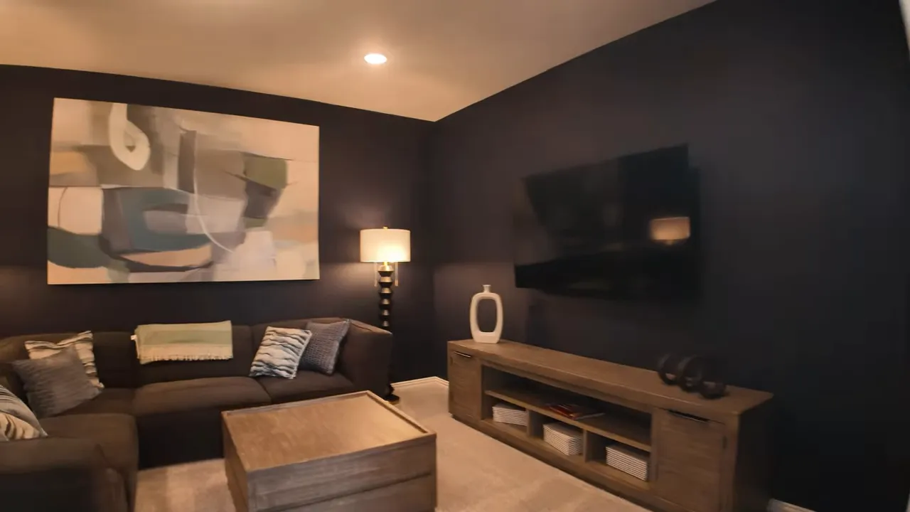media room with sectional sofa coffee table lamps wall art and tv