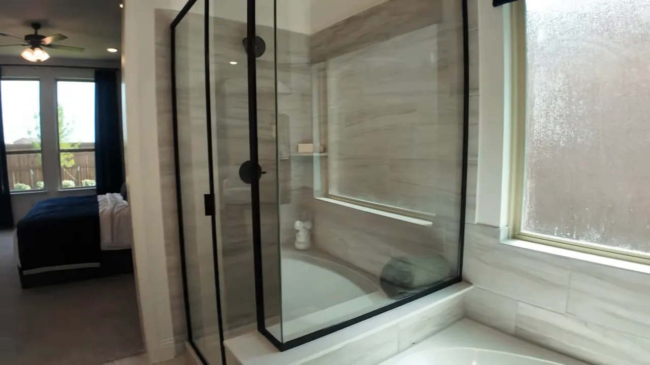 primary bathroom with glass shower large tub and window