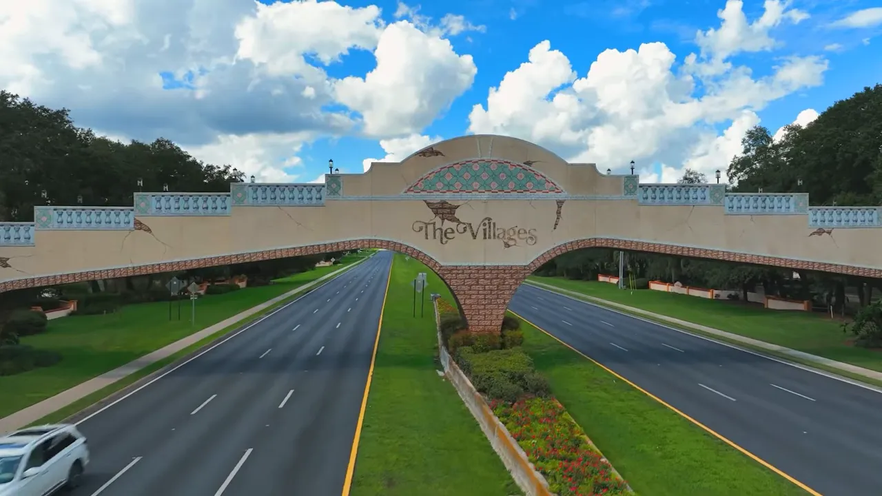 The Villages entrance sign with road and landscaped surroundings under a blue sky
