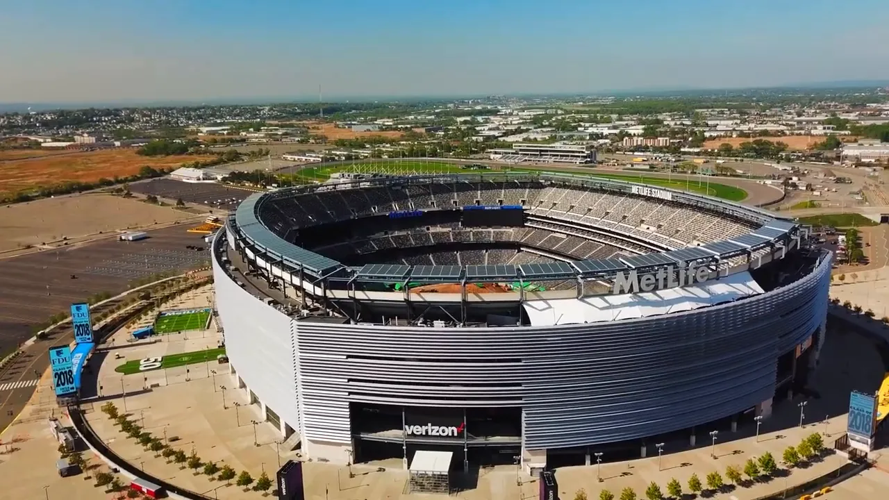 Aerial view of MetLife Stadium with parking lots and city in the background