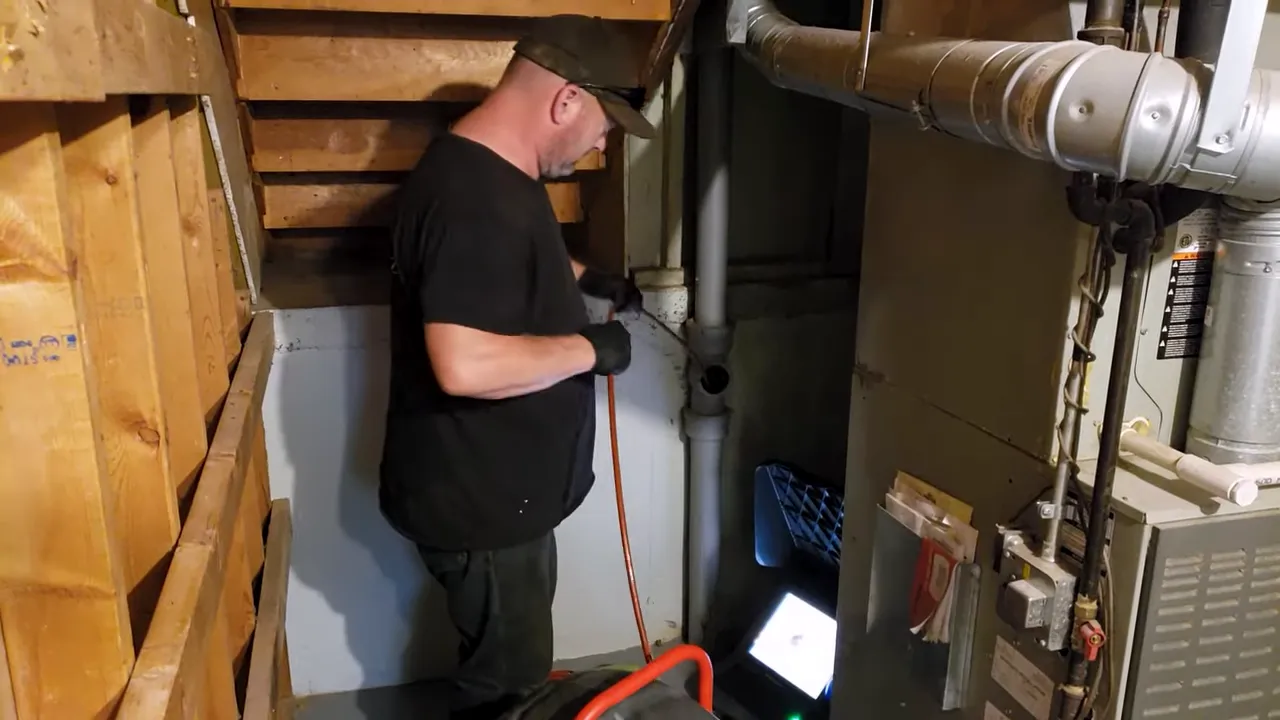 Inspector performing a sewer scope inspection with camera equipment near main plumbing lines