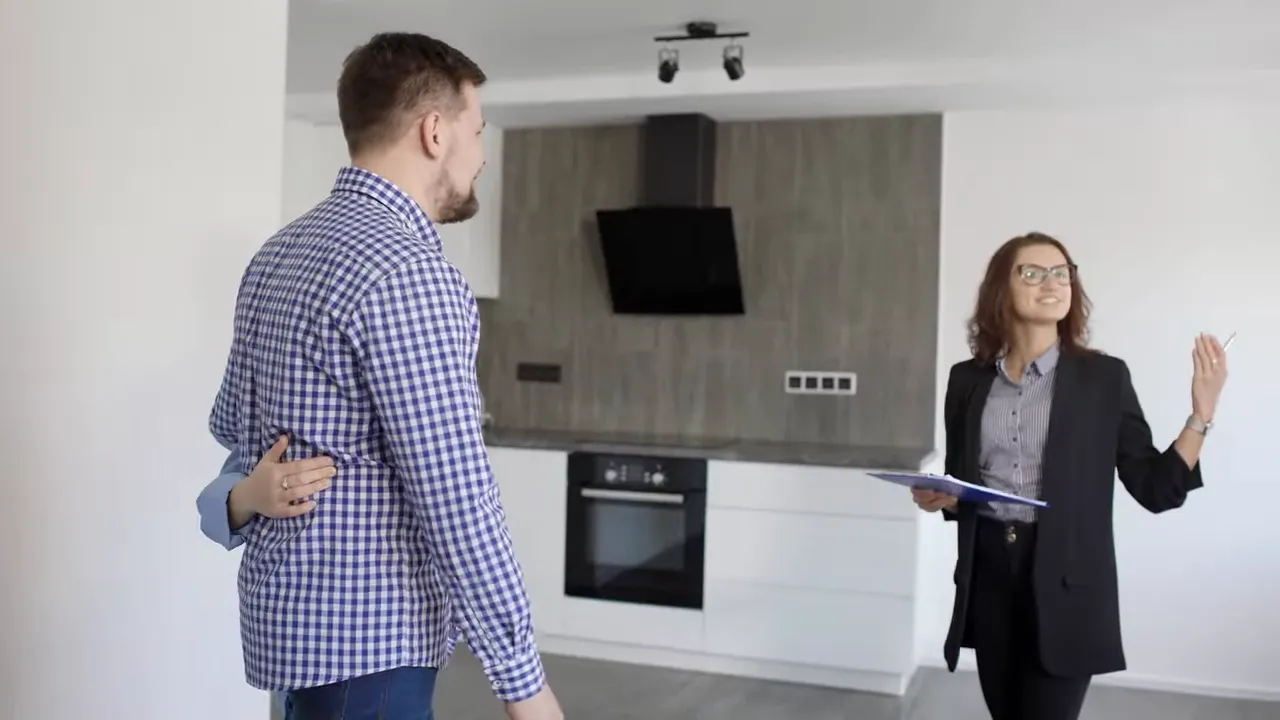 Real estate showing a modern kitchen while buyers review documents with an agent during a condo showing