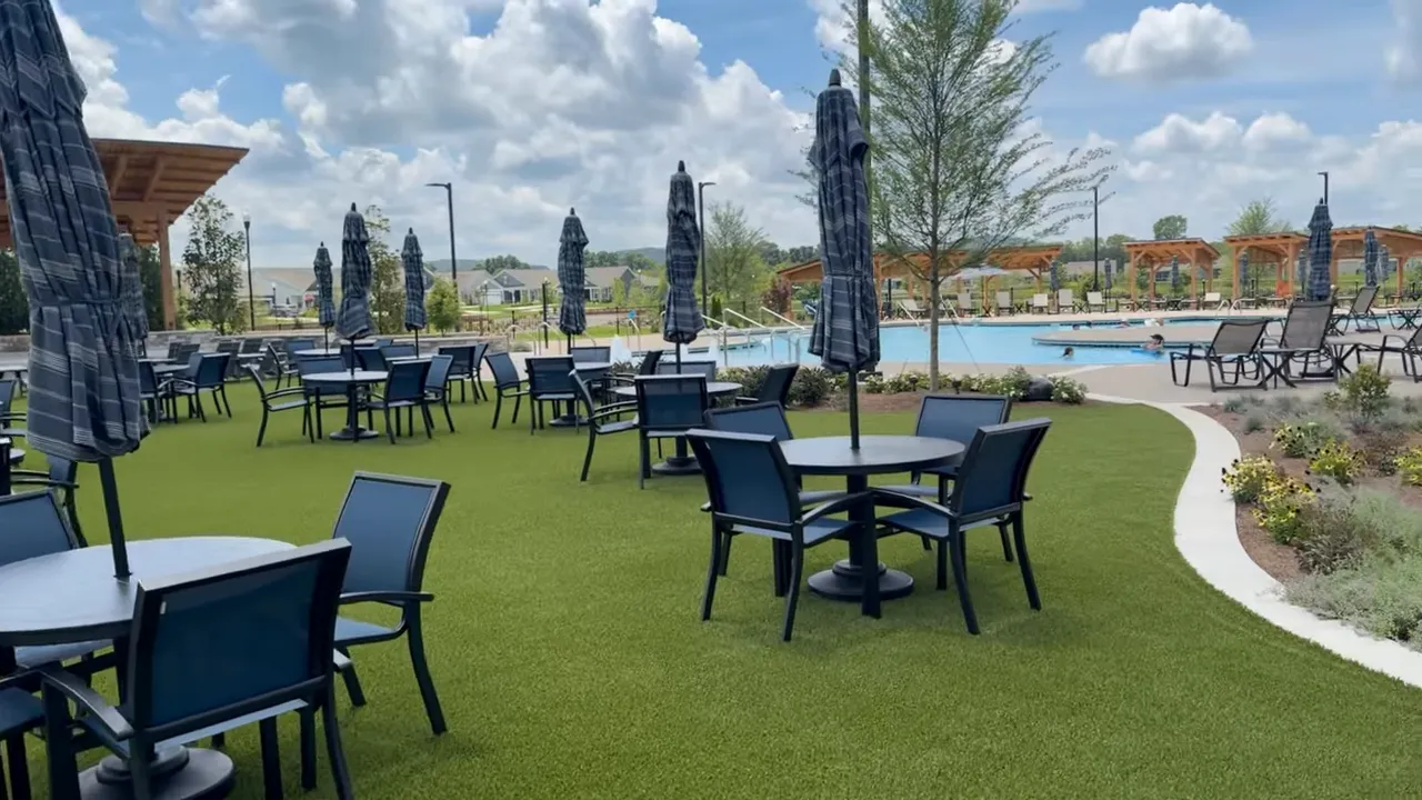 Outdoor lawn seating tables umbrellas and pool area near amphitheater