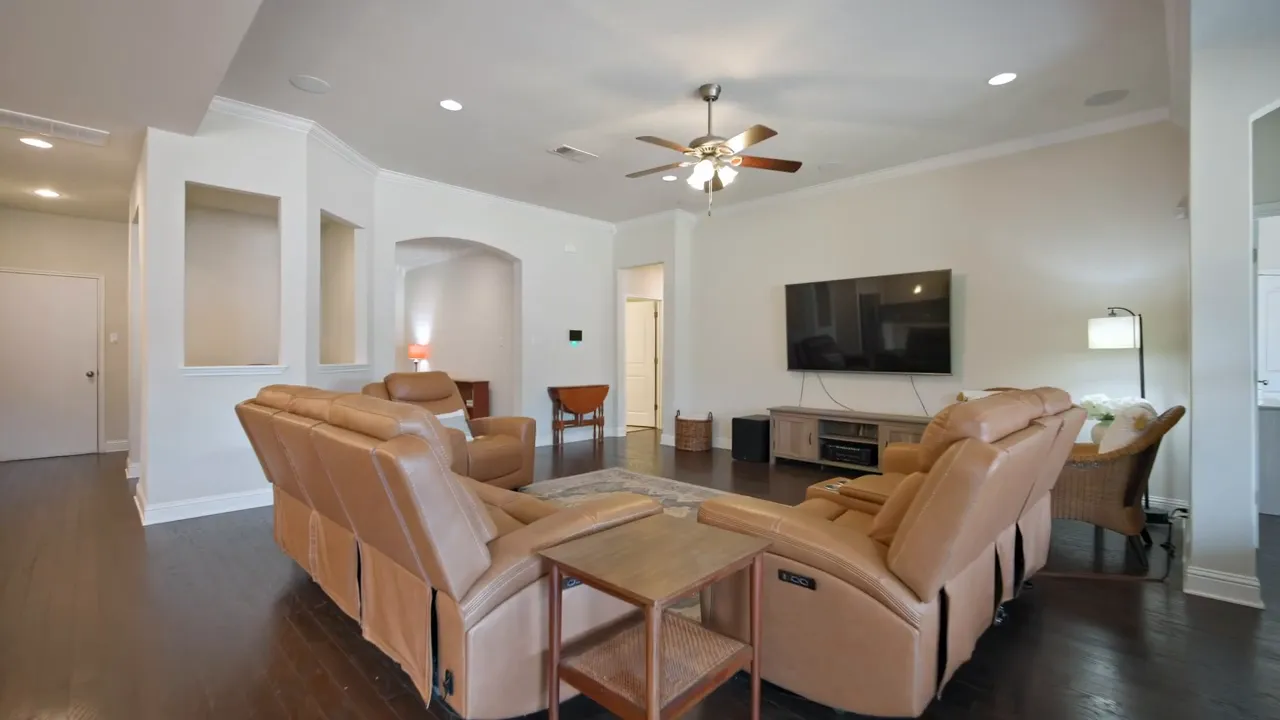 Spacious living room with leather recliners, a large TV and open flow to adjacent rooms