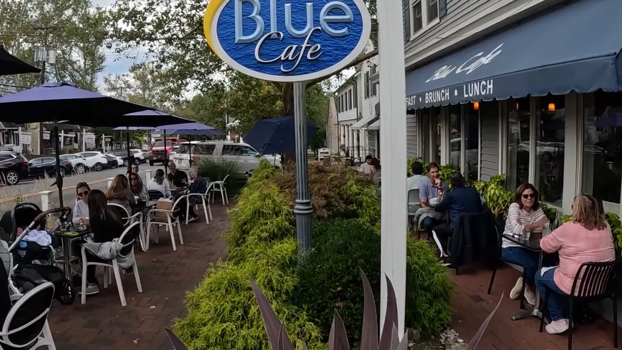 Blue Cafe storefront sign with outdoor dining patio along a small-town main street