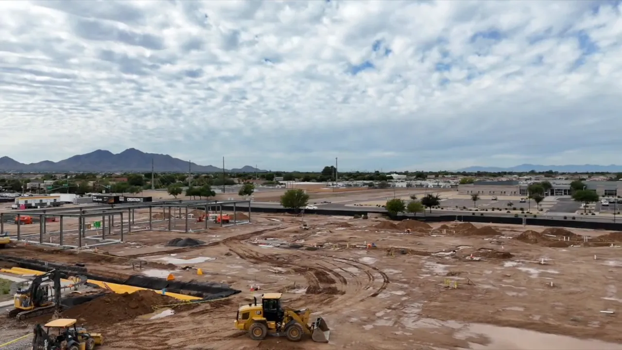 Large desert construction site with grading equipment and mountains in the distance