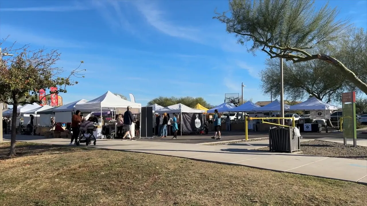 Outdoor market with white vendor tents people and desert trees
