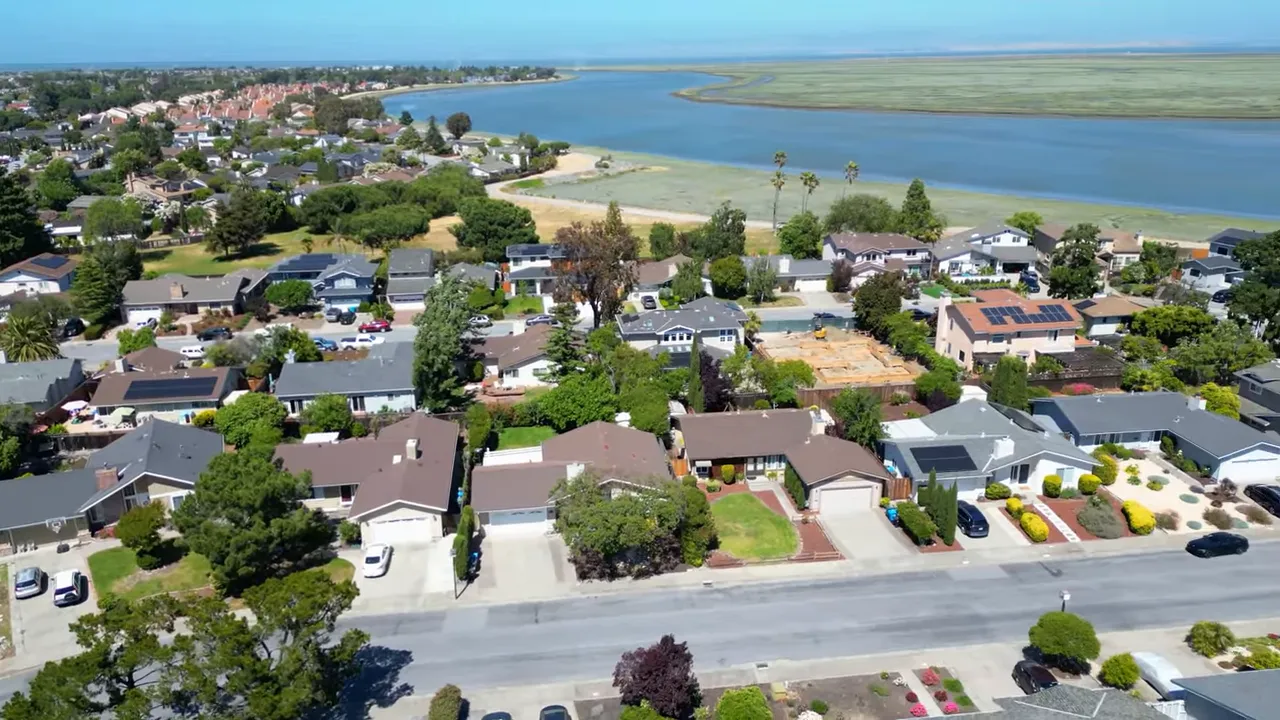 Wide aerial shot of houses along the bay edge with marshland and lagoons