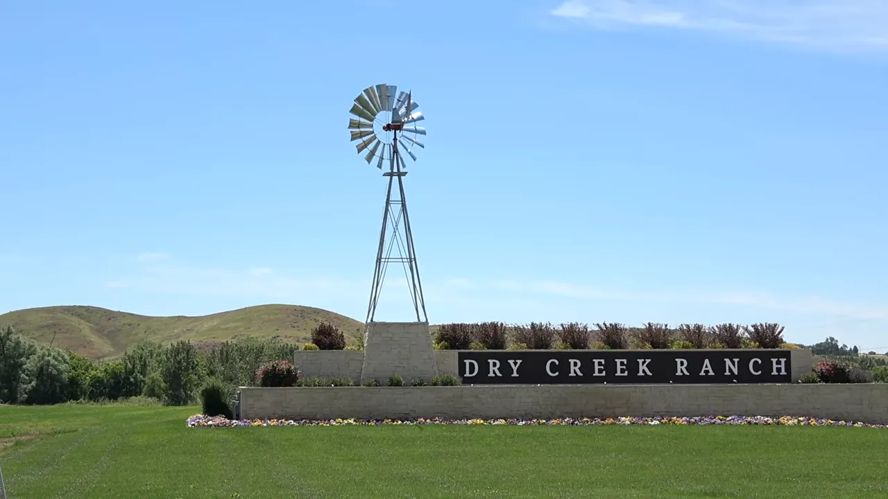 Entrance sign for Dry Creek Ranch with a windmill and landscaped grounds