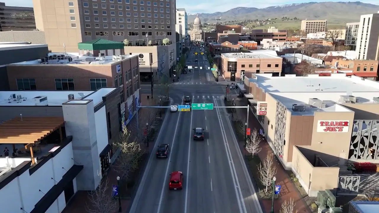 Downtown Boise street with cars buildings and traffic lights looking toward the foothills