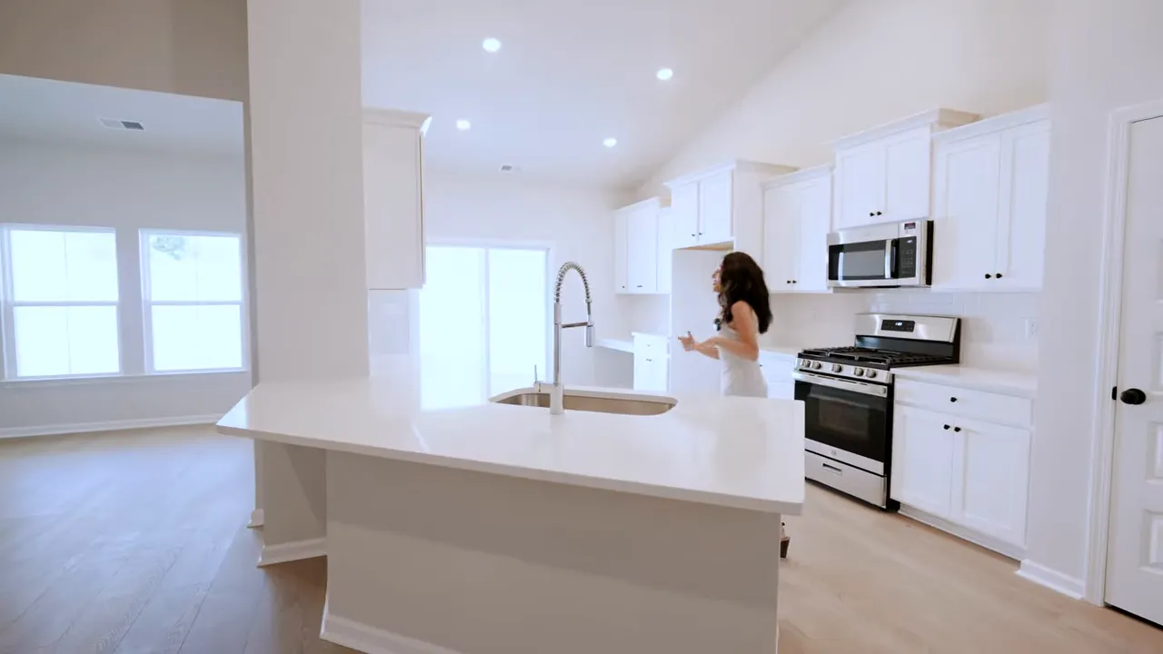Kitchen with white shaker cabinets, large island, farmhouse-style sink, and gas range in a new home near Cherry Grove Beach
