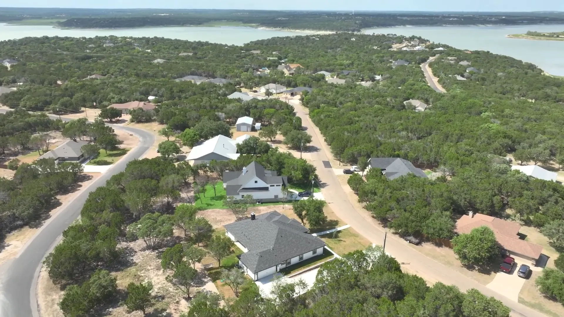 Aerial neighborhood view with streets, homes and the lake visible on the horizon showing community layout